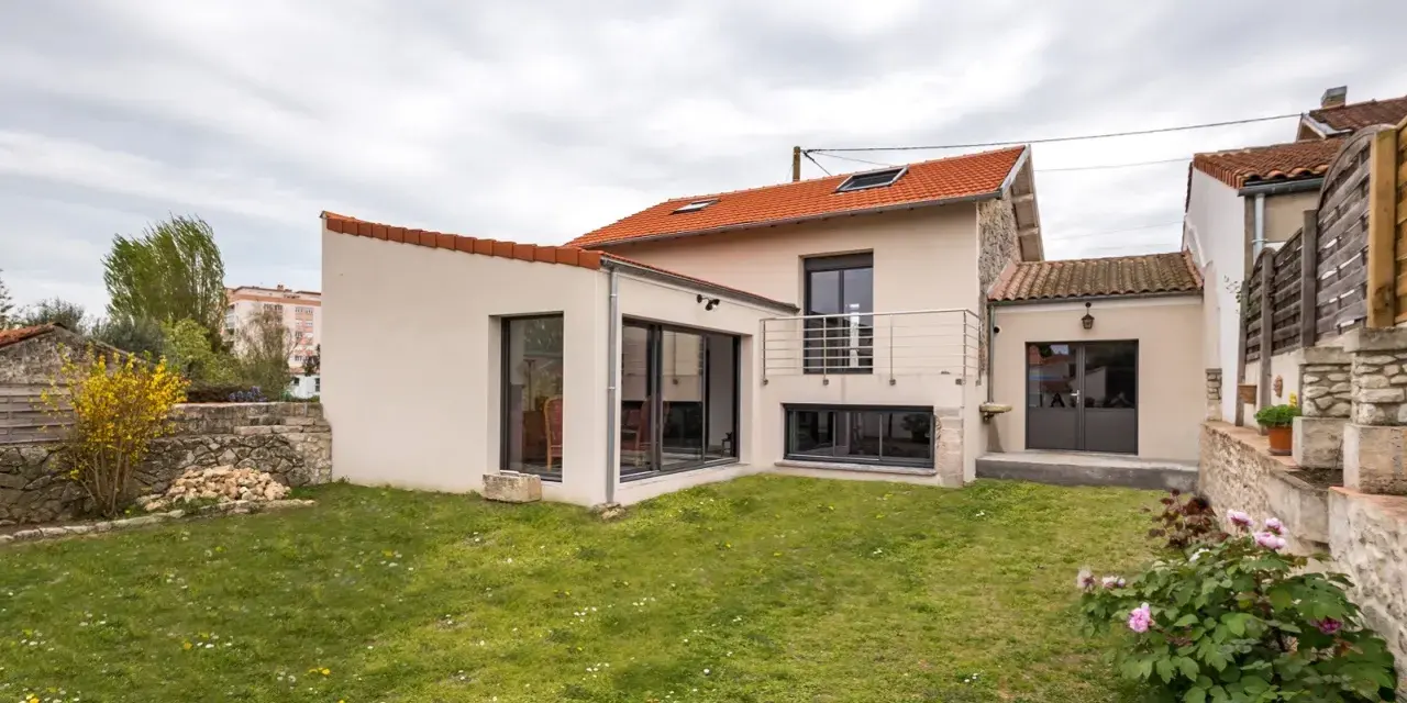 Maison avec extension moderne, jardin verdoyant. Le prix d'une extension maison 20m2 peut varier, mais ce type d'agrandissement offre un espace de vie supplémentaire.