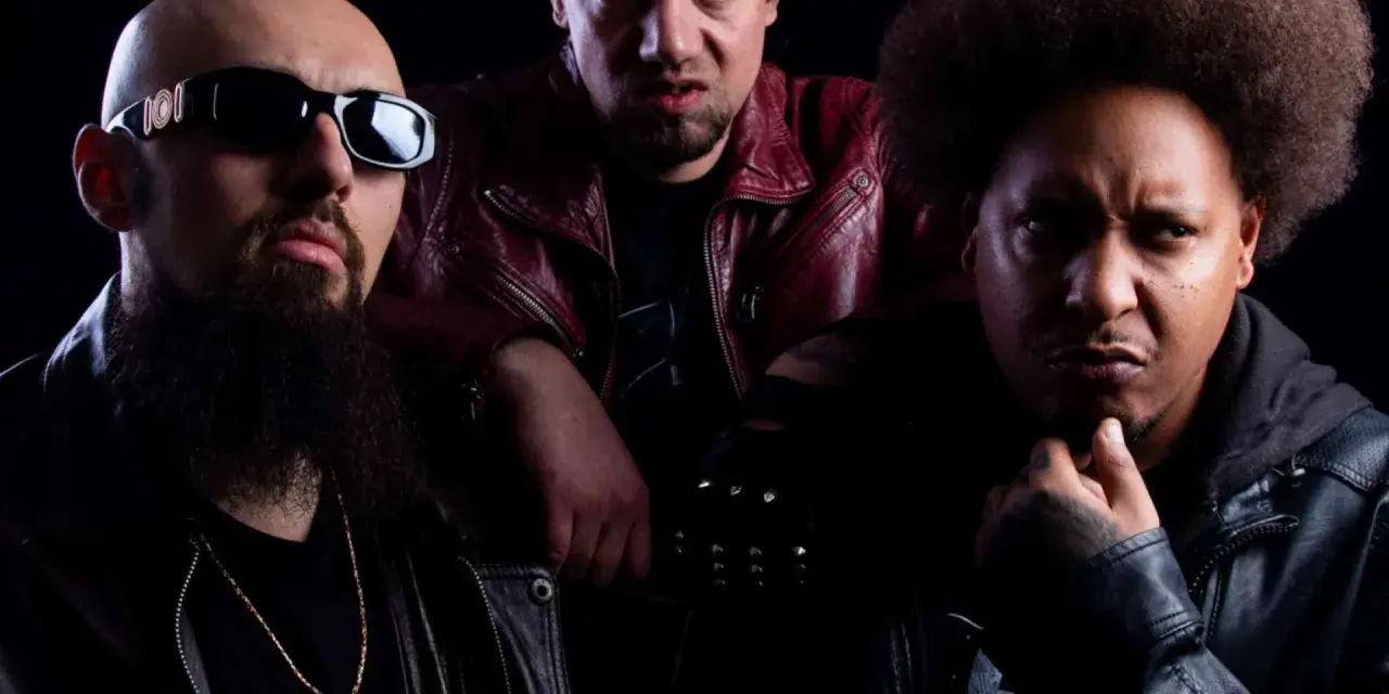 Trois hommes au look sombre, dont un avec des lunettes de soleil et une barbe, un autre avec des yeux jaunes et une veste rouge, et le troisième avec une afro. Un trio dope dod.