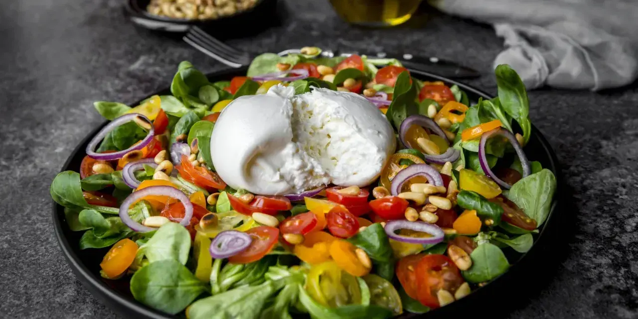 Frischer Salat mit Burrata, Tomaten, Zwiebeln und Pinienkernen. Perfekt für eine leichte Mahlzeit, auch in der Schwangerschaft.