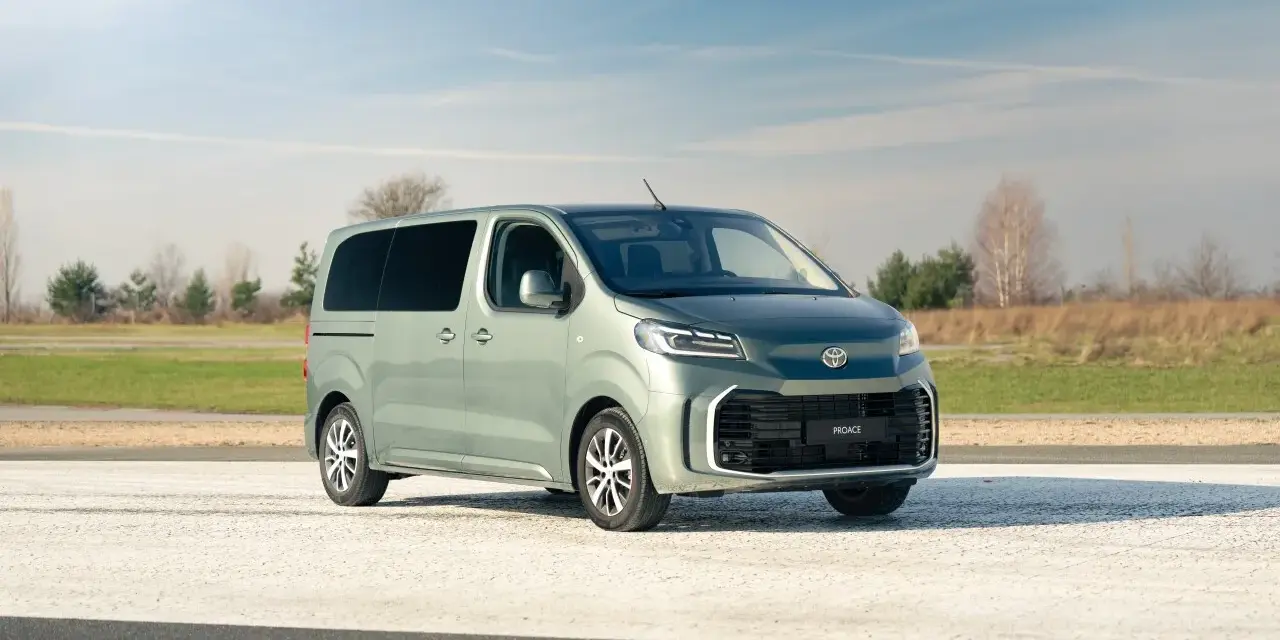 Nowy, zielony minivan Toyota Proace na tle nieba i pól. Idealny na rodzinne wycieczki.