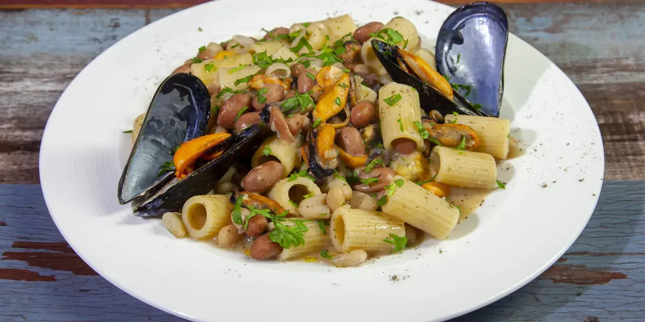 Piatto di pasta fagioli e cozze, con rigatoni, fagioli borlotti e cannellini, cozze nere e prezzemolo tritato.