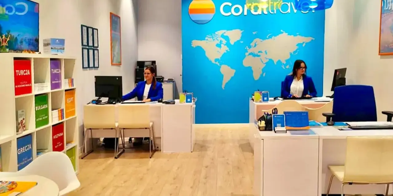Biuro podróży Coral Travel z pracownicami za ladą i mapą świata na ścianie.