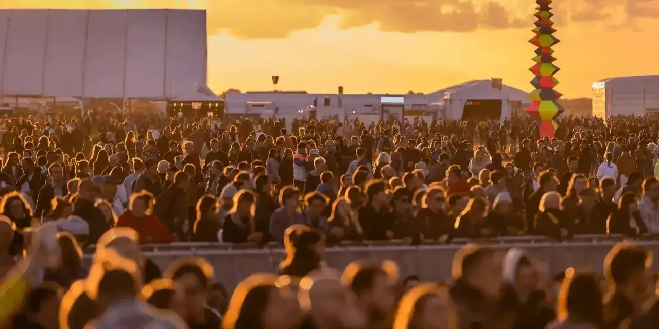 Tłum ludzi na festiwalu, zachód słońca. Kolorowa instalacja artystyczna w tle. Kto będzie następny na scenie?