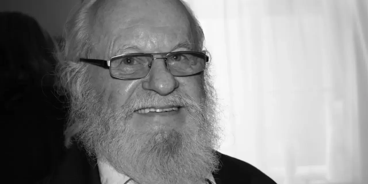 Uśmiechnięty Aleksander Skowroński z siwą brodą i okularami.