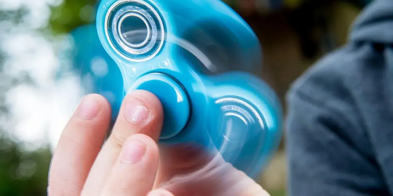 En blå finger spinner snurrar snabbt i handen, med suddiga kanter som visar rörelsen.