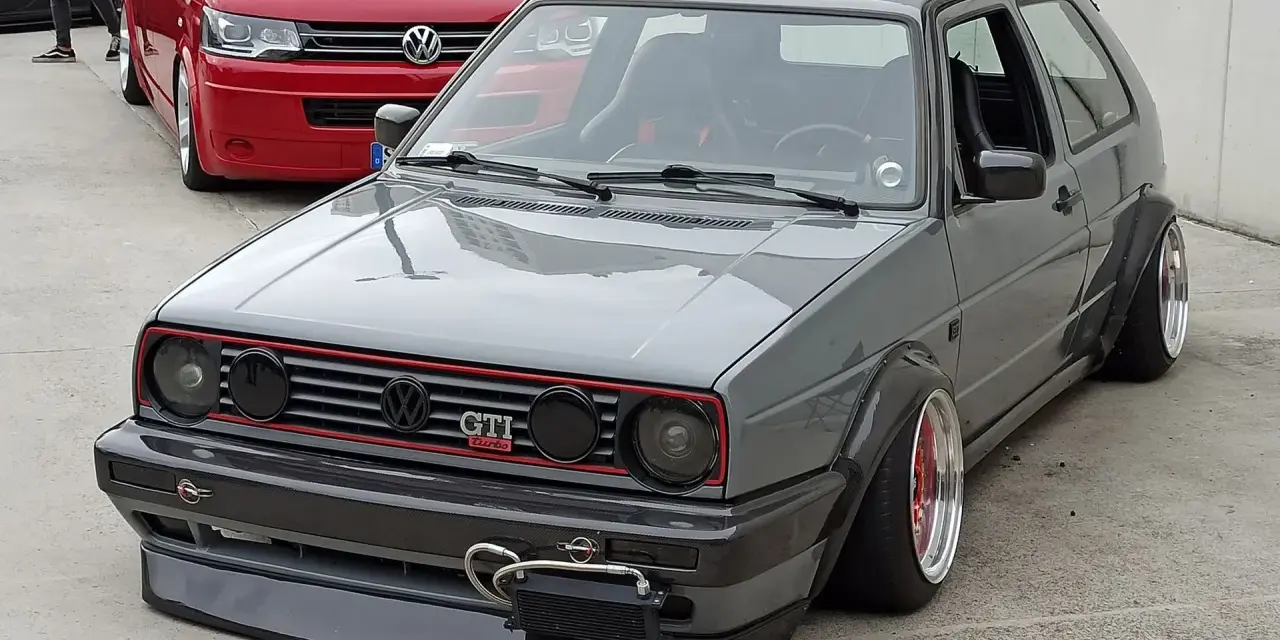 Szary, zmodyfikowany Volkswagen Golf GTI z szerokimi błotnikami i spojlerem.