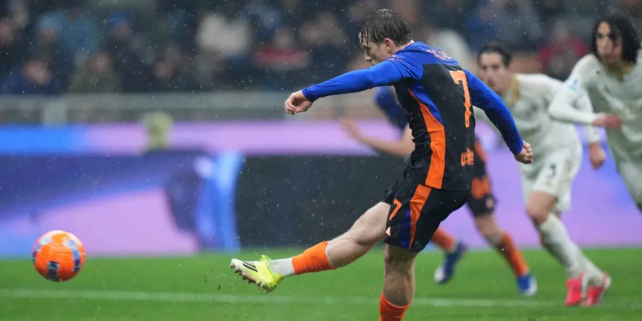 Piłkarz w niebiesko-czarnej koszulce z numerem 7 strzela gola w deszczu podczas meczu Inter Mediolan – AS Roma.