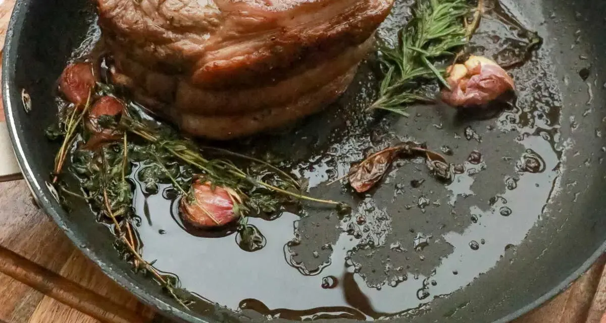 Rouelle de porc au barbecue, rôtie dans une poêle avec de l'ail et des herbes aromatiques, prête à être dégustée.