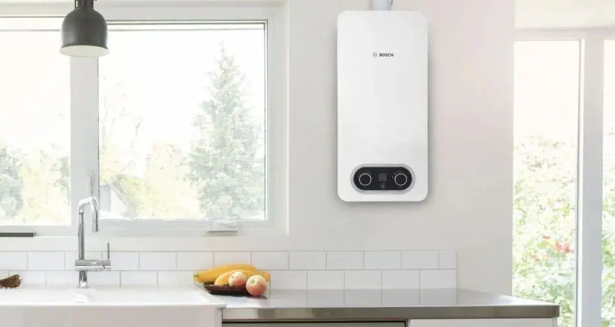 Scaldabagno a gas Bosch bianco, con pannello di controllo digitale, montato a parete in una cucina moderna.