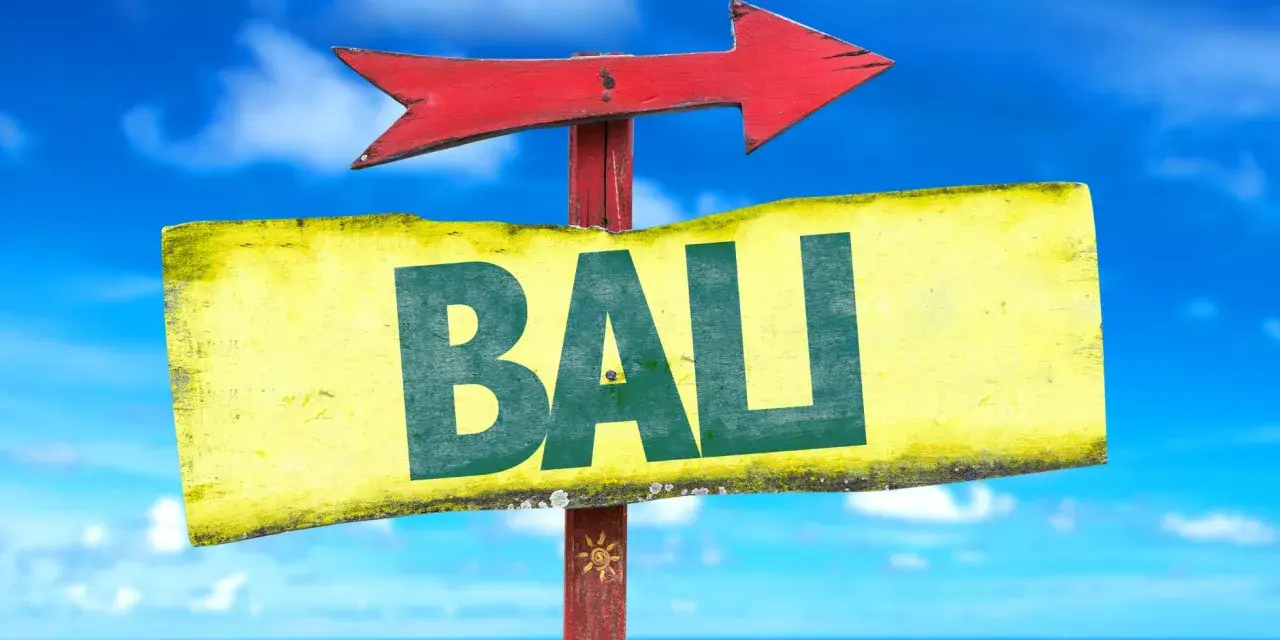 Strzałka kierunkowa wskazuje drogę do Bali. W tle błękitne niebo i morze.