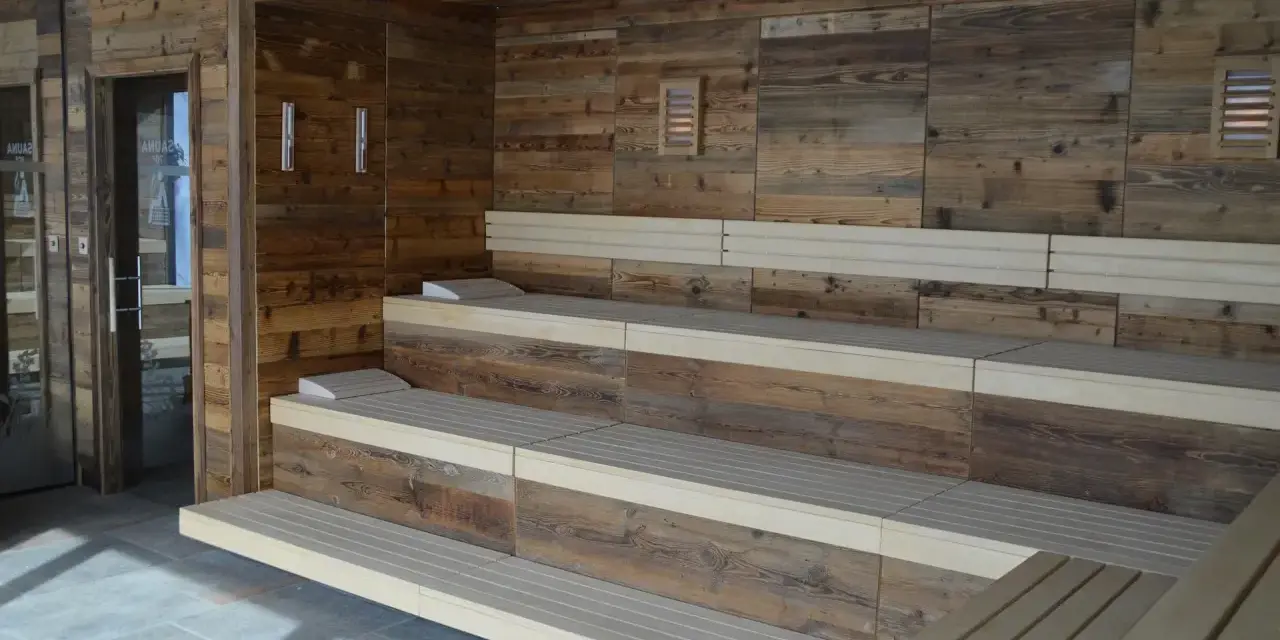 Drewniana sauna w domu z wielopoziomowymi ławami i kamienną podłogą. Idealne miejsce na relaks.