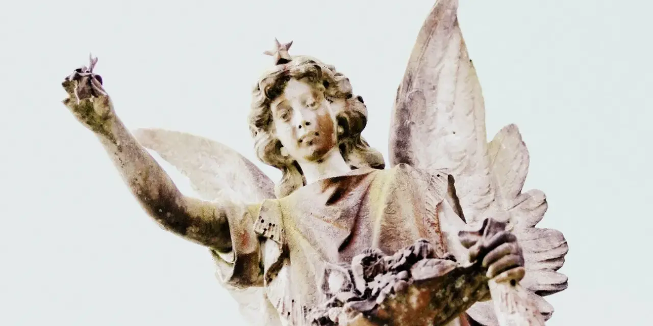 Kamienna figura anioła z gwiazdą na głowie, trzymająca w dłoniach kwiaty i gałązkę. Symbolika 2244 znaczenie.