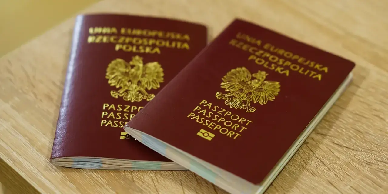 Dwa polskie paszporty leżące na drewnianym blacie.