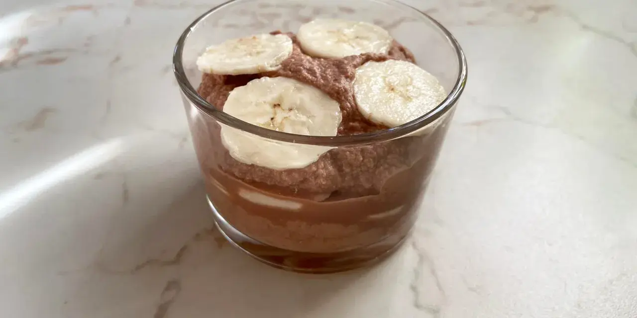 Schokoladiger Genuss: Ein Glas mit luftiger Nutella-Creme mit Mascarpone, garniert mit frischen Bananenscheiben.