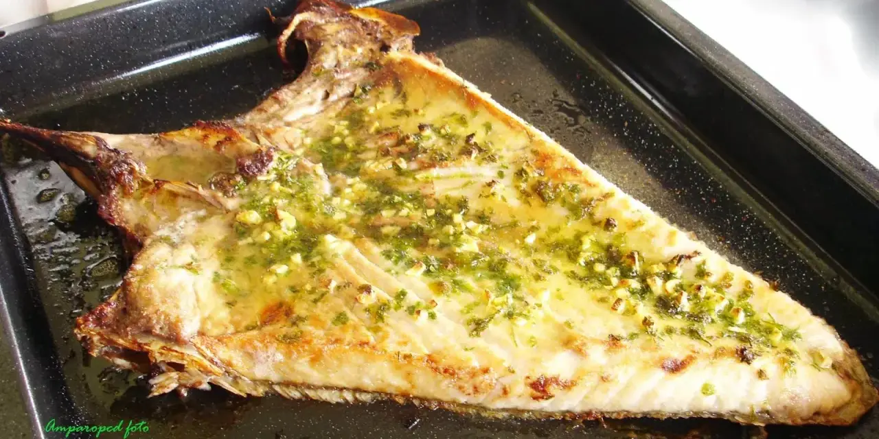 Deliciosa ventresca al horno, dorada y jugosa, con un aderezo de ajo y perejil que invita a probarla.