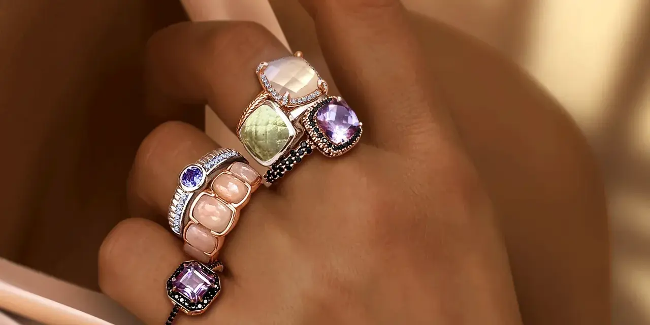 Dita adornate con anelli che esaltano il loro fascino, un vero **materiale prezioso** che cattura la luce.