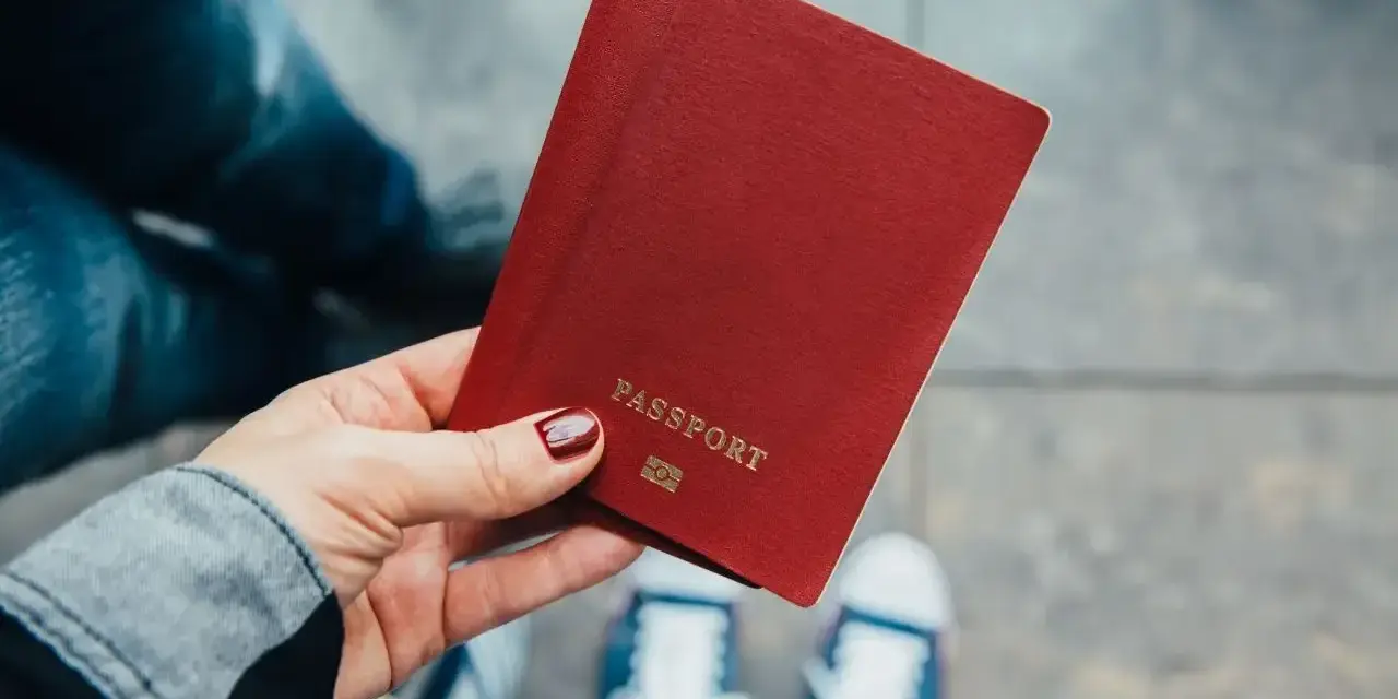 Dłoń trzyma paszport. Zastanawiasz się, ile kosztuje zmiana nazwiska? Czas na podróż i nowe życie!