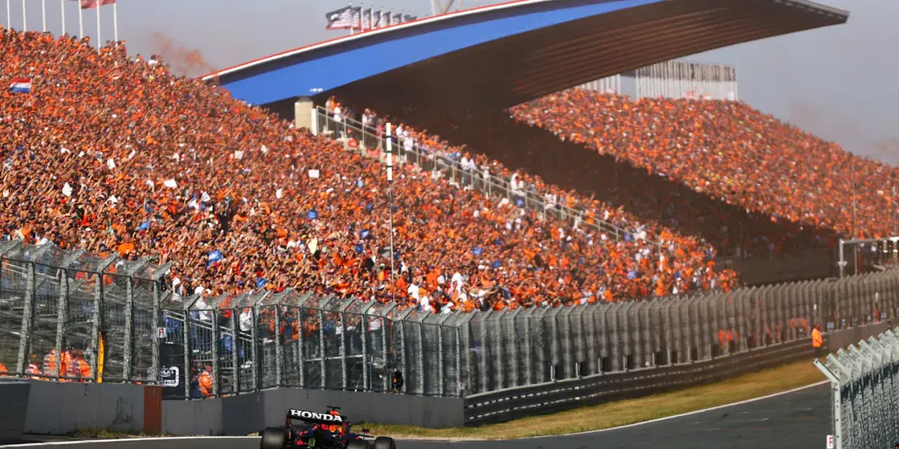 Un coche de Fórmula 1 compite en el Dutch Grand Prix ante una multitud masiva vestida de naranja.
