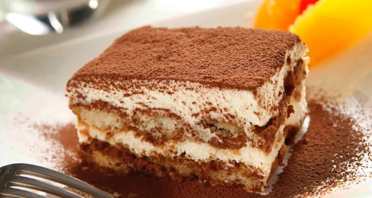 Pyszne tiramisu Ani Starmach, posypane kakao, z owocami i wisienką. Idealne na deser.