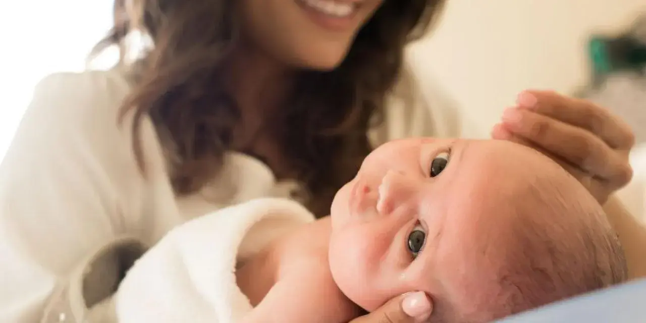 Lächelnde Mutter hält ihr Baby, das gerade einen Wachstumsschub durchmacht.