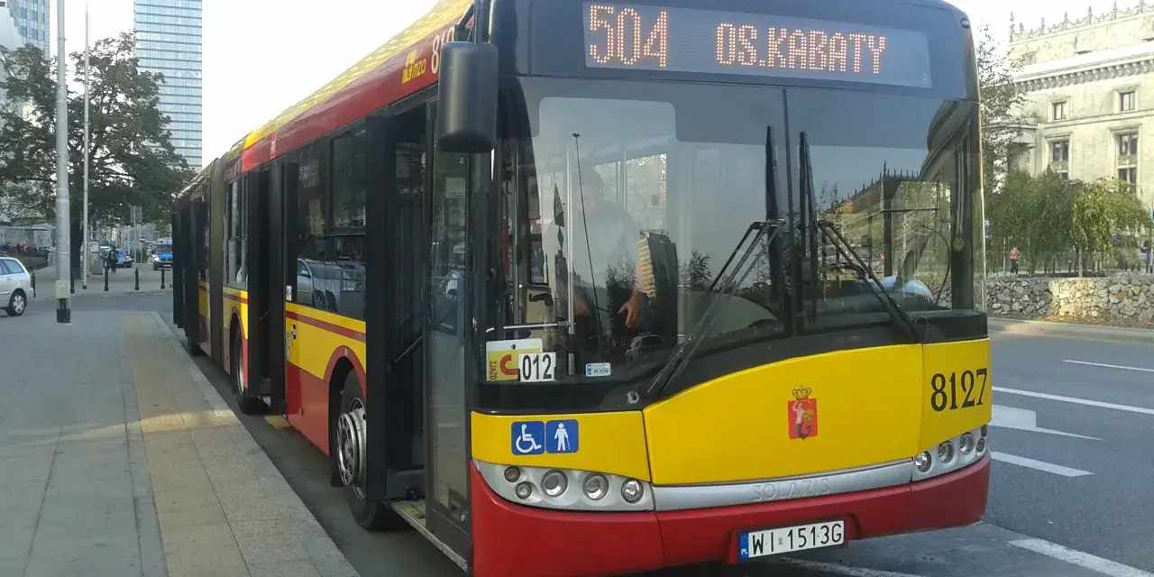 Autobus 504 OS.KABATY z numerem bocznym 8127 stoi na przystanku. W tle widać nowoczesne budynki.