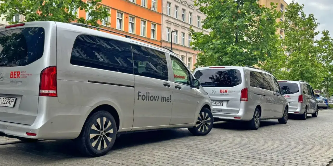 Srebrne vany z napisem "Follow me!" i logo BERLIN BRANDENBURG AIRPORT. Idealne, by dowiedzieć się, jak dojechać na lotnisko Berlin Brandenburg.