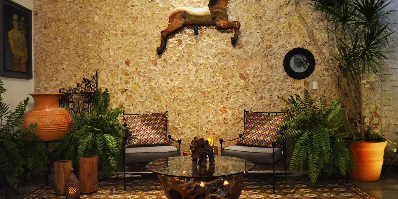 Un caballo decorativo adorna la pared de un patio exterior, complementado por plantas exuberantes y un rincón acogedor.