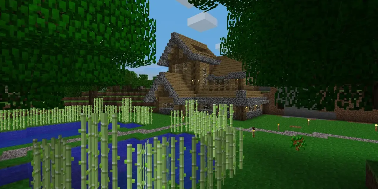 Drewniany dom z kamiennymi elementami, otoczony bambusami i wodą. W Minecraft można budować takie cuda i tworzyć własne światy.
