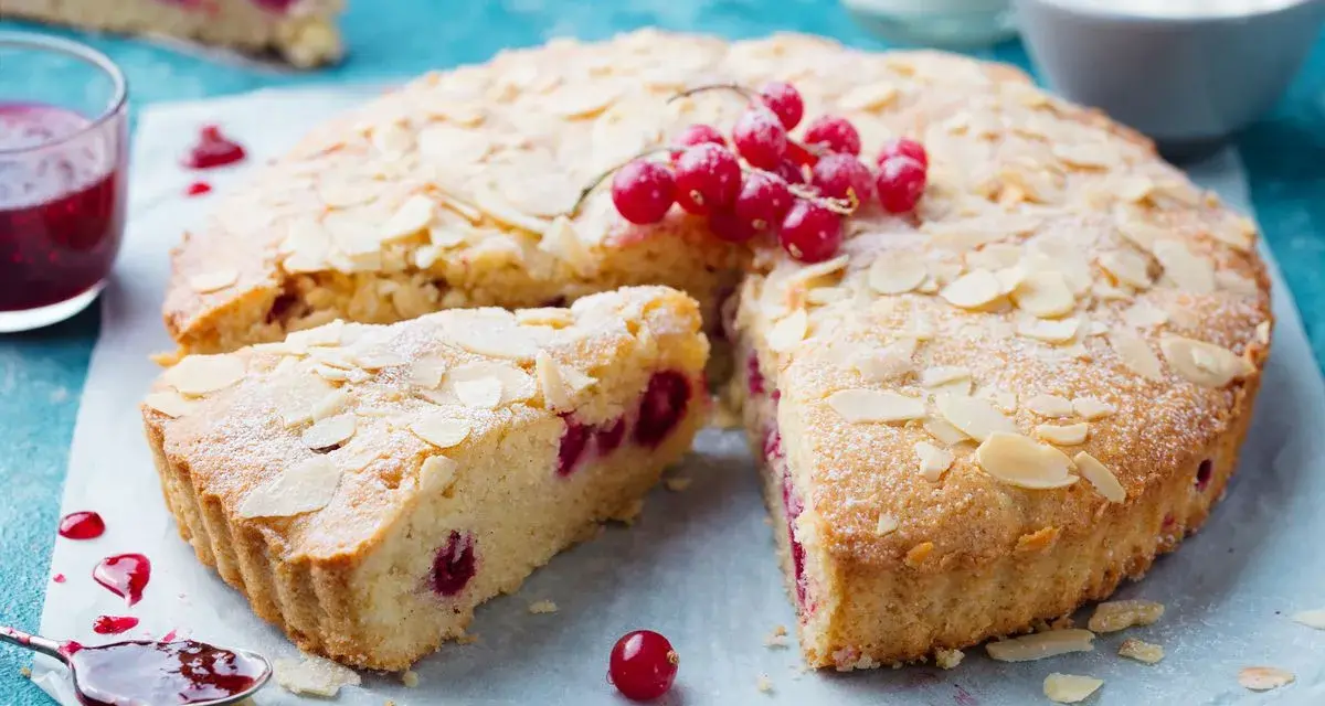 Saftiger zitronenkuchen ohne mehl, mit roten Johannisbeeren und Mandelblättchen bestreut. Ein Genuss!