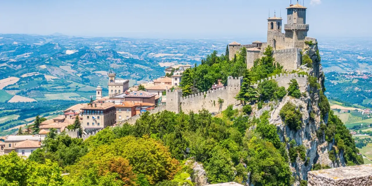 Trzy wieże obronne górują nad malowniczym krajobrazem San Marino, otoczone zielenią i historyczną zabudową.
