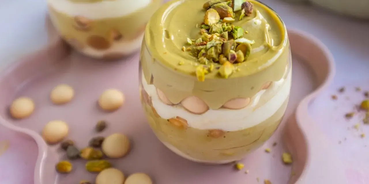 Pyszny deser w pucharku: krem pistacjowy z mascarpone, przełożony biszkoptami i posypany pistacjami.