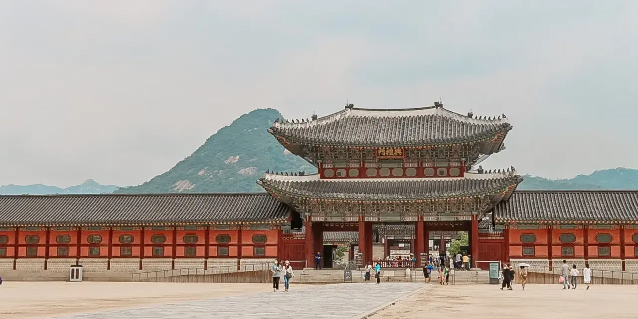 Zwiedzający pałac w Seulu, podziwiający architekturę. Czy Korea Południowa jest bezpieczna? Tak, to kraj przyjazny turystom.