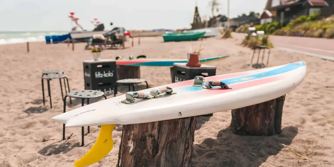 Windsurfbrett am Strand, ein echter Dahme Geheimtipp für Wassersportler. Gelbe Finne ragt aus dem Sand.