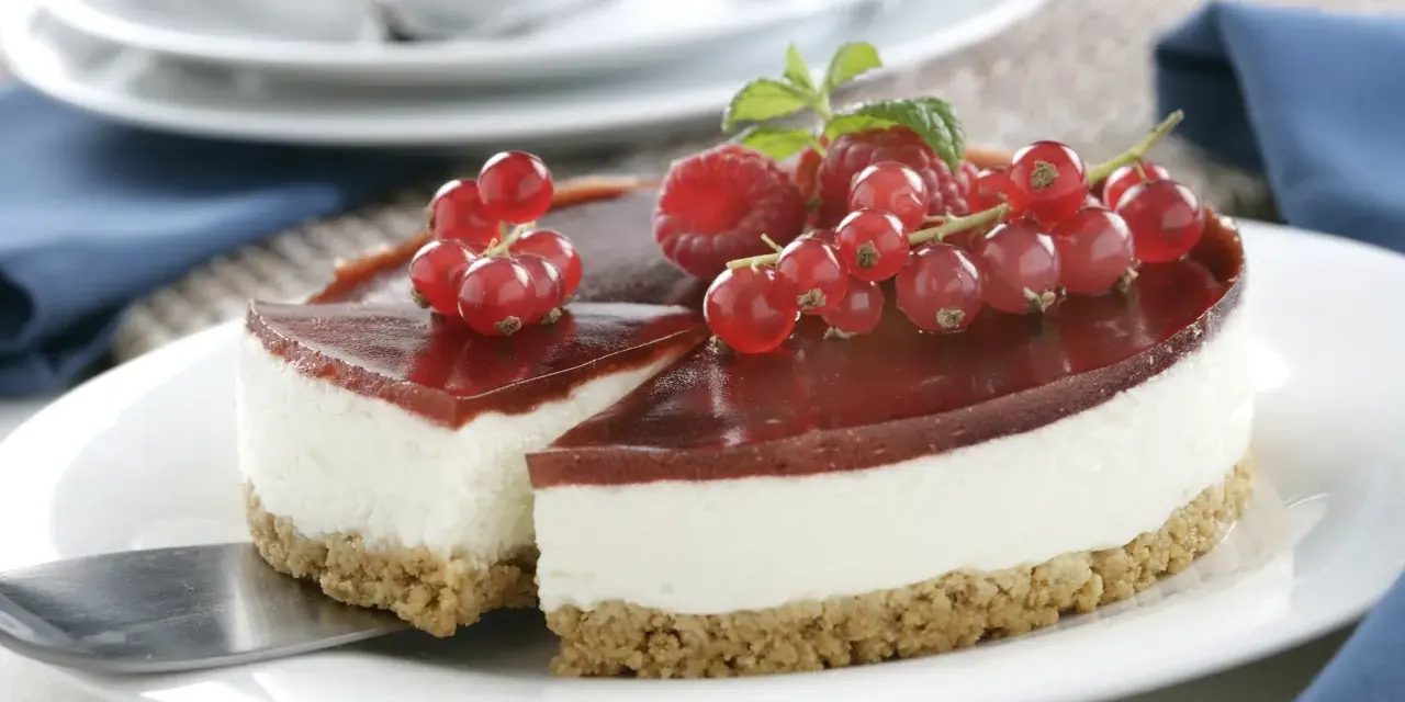 Tarta de queso Philadelphia con frutos rojos y gelatina de fresa, lista para servir.