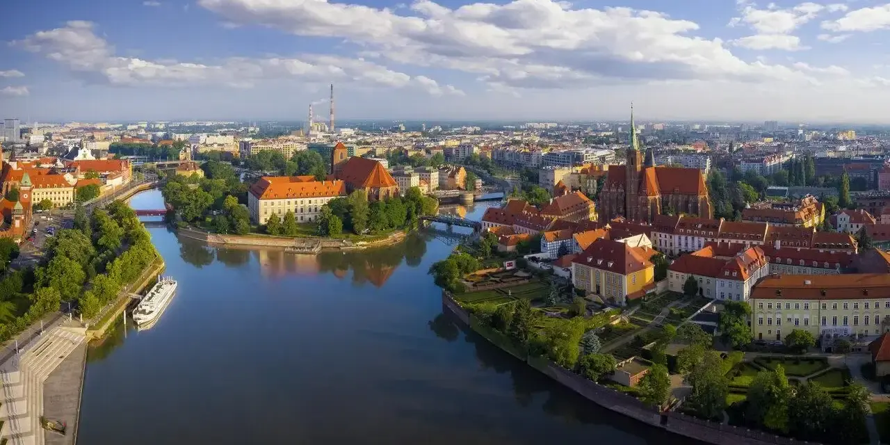 Majówka we Wrocławiu: malowniczy widok na Ostrów Tumski z rzeką i zabytkowymi budynkami.