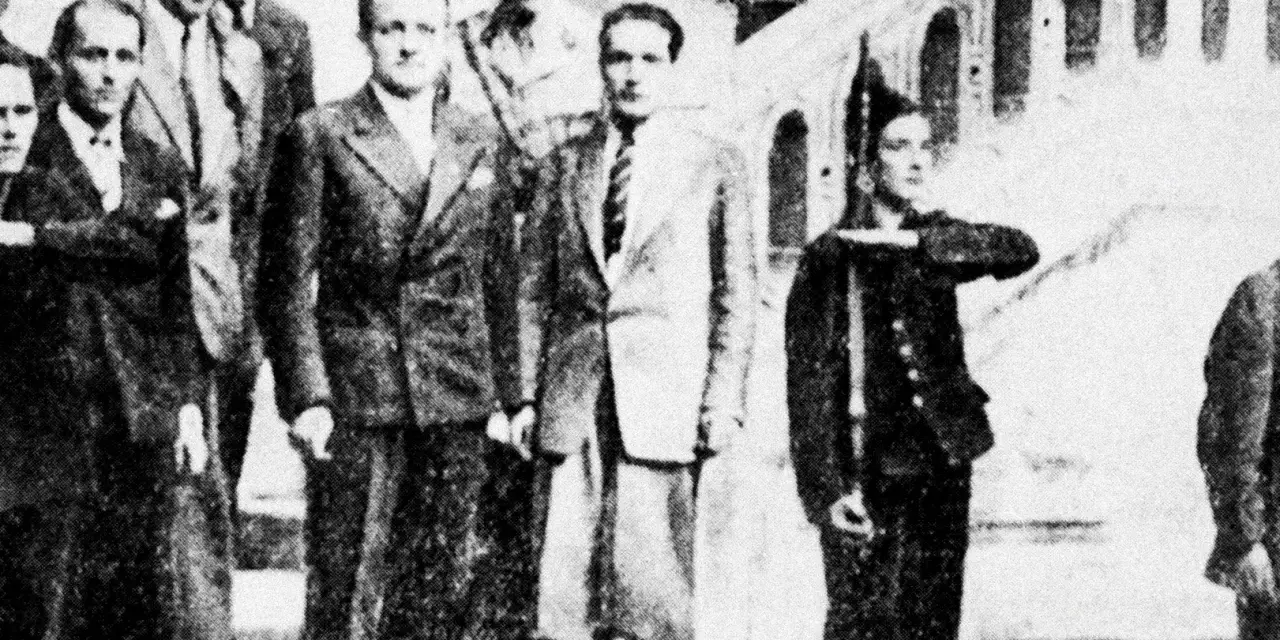 Groupe d'hommes en costume, dont Henri Frenay et François Mitterrand, posant devant un escalier.