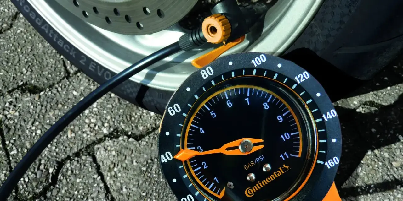 Manometro Continental per pneumatici moto, collegato alla ruota. La lancetta indica la pressione.