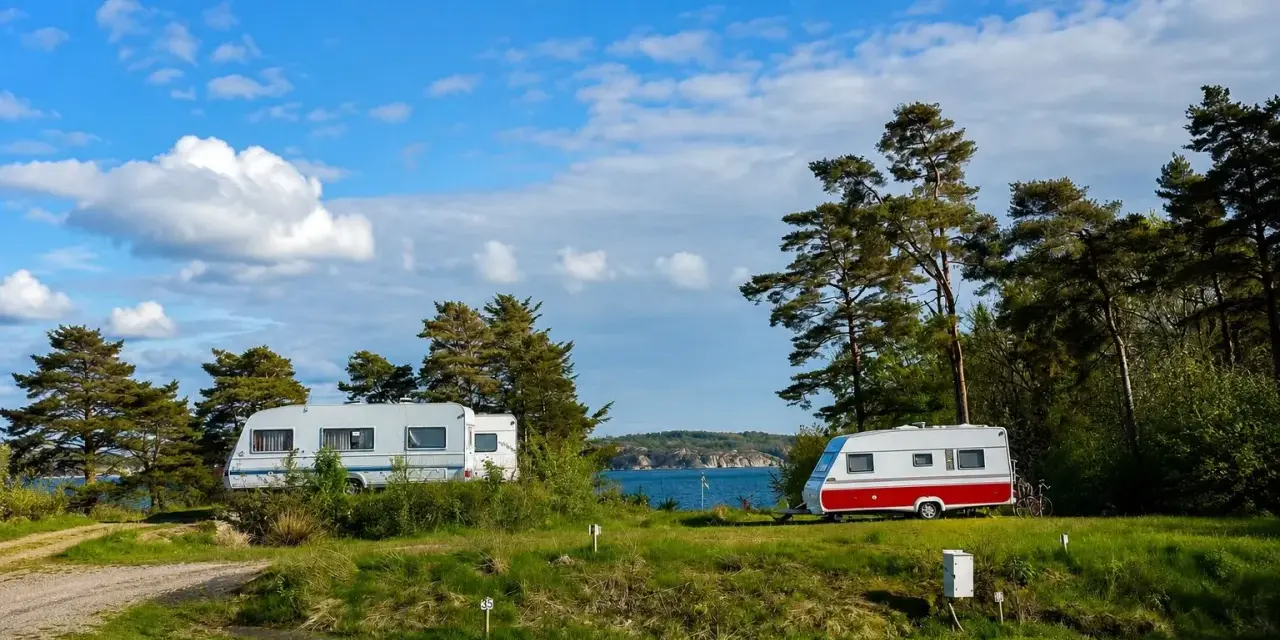 Två husvagnar på en grönskande campingplats vid havet i Lysekil. Blå himmel med vita moln.