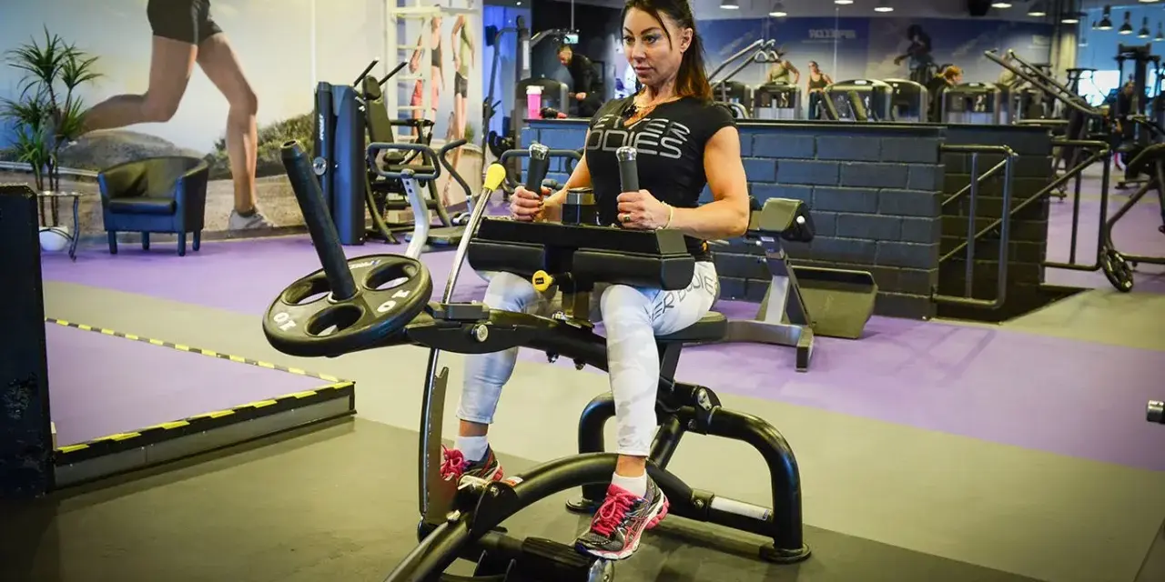 Kvinna tränar på gymmaskin. Hon har på sig träningskläder och fokuserar på sin träning. Hon verkar vara en seriös atlet som tar sin vad press på allvar.