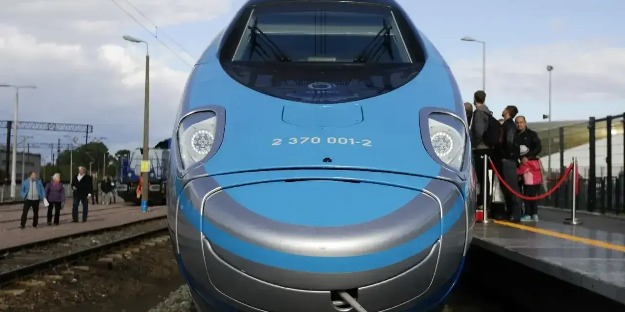 Pendolino Kraków Gdańsk cena: nowoczesny pociąg na torach, pasażerowie czekają na peronie.