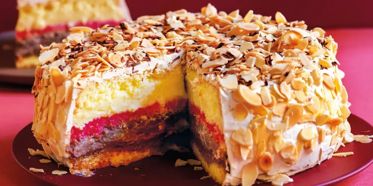 Una fetta di pizza dolce abruzzese, stratificata con crema, cioccolato e confettura, ricoperta di mandorle tostate e scaglie di cioccolato.
