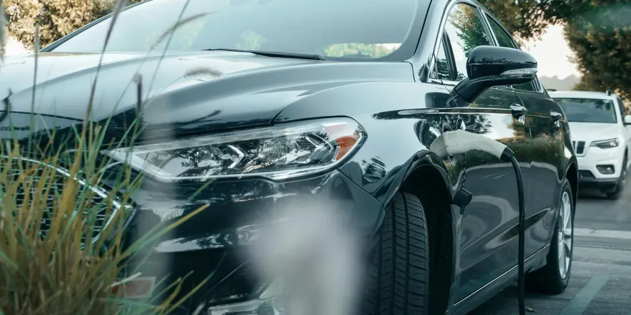 Ciemna toyota hybryda podłączona do ładowarki, gotowa na ekologiczną podróż.