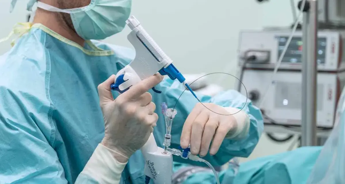 Lekarz w masce i rękawiczkach trzyma urządzenie do biopsji prostaty.