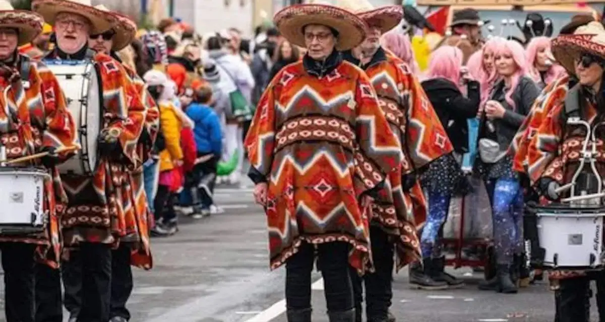 Menschen in bunten Ponchos und Sombreros marschieren mit Trommeln. Sie feiern Fasching, eine Zeit voller Freude und Verkleidungen.