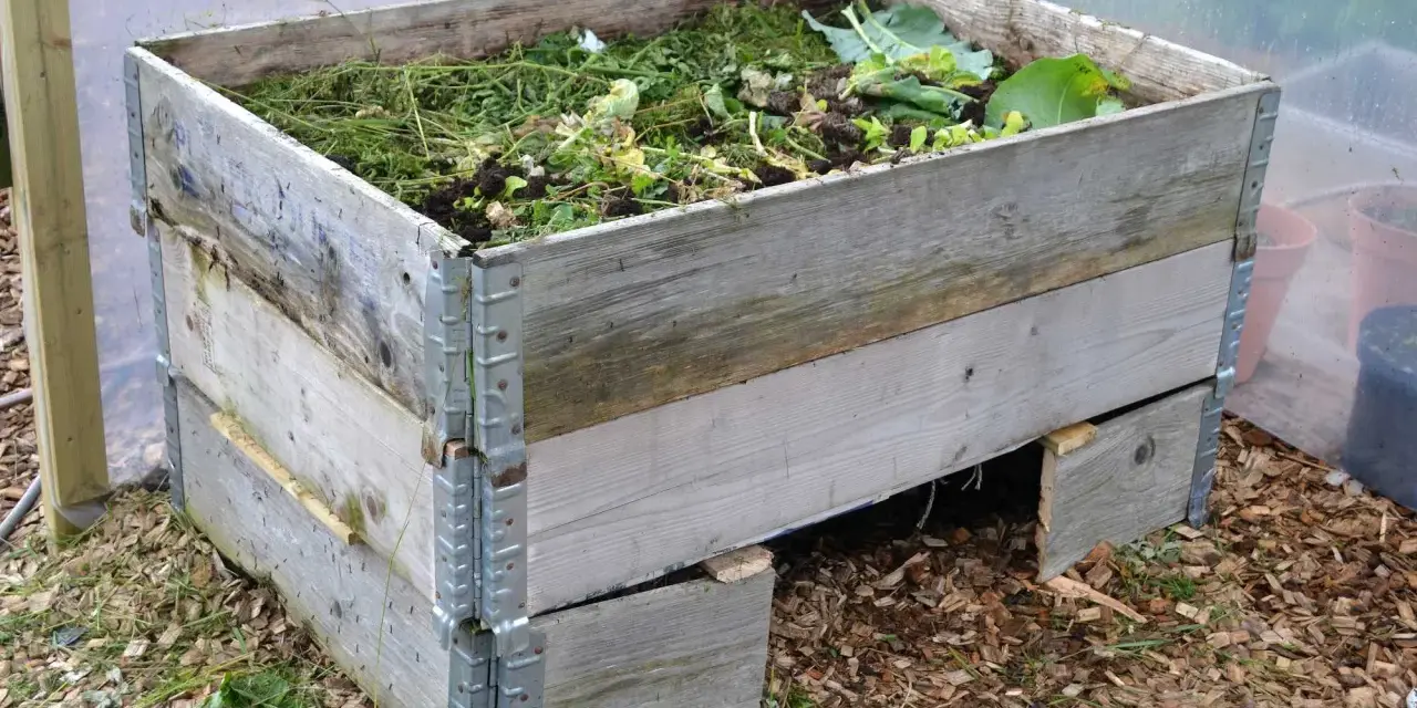 En kompost av pallkragar fylld med trädgårdsavfall. Enkel och effektiv lösning för att bygga kompost.