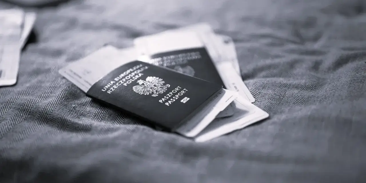 Polskie paszporty leżą na tkaninie, symbolizując długi pobyt w Polsce i plany na pobyt za granicą.