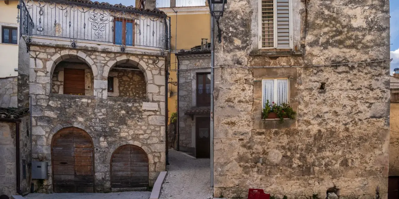 Antico borgo in pietra, con archi e balcone in ferro battuto. La **pretoro altitudine** offre scorci suggestivi tra vicoli acciottolati e case antiche.