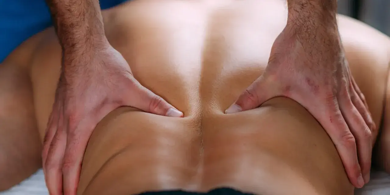Hände massieren den Rücken eines Mannes. Eine wohltuende Massage kann bei einem Bandscheibenvorfall Linderung verschaffen.