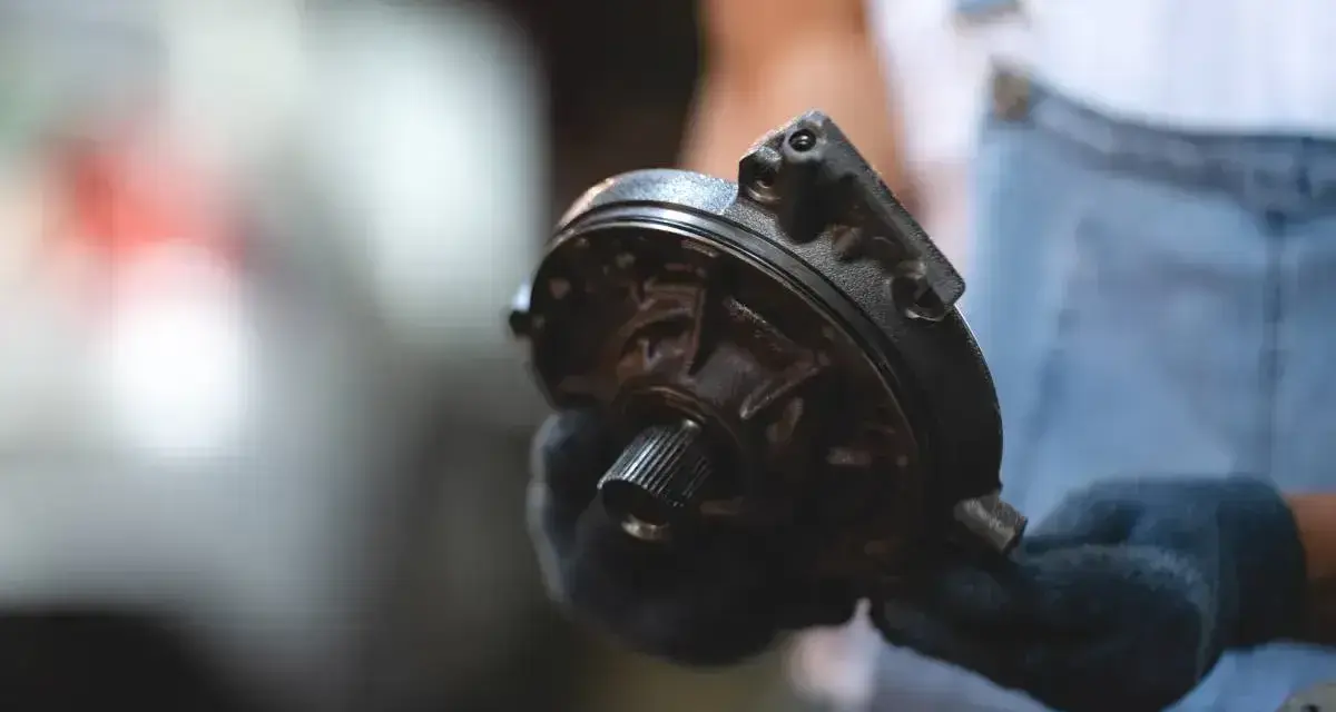 Mechanik trzyma element serwa hamulcowego. Objawy awarii mogą być różne, np. twardy pedał hamulca.