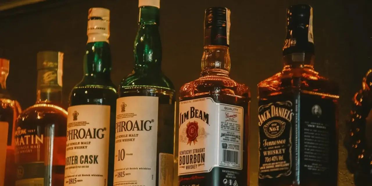 Rząd butelek whisky, w tym Laphroaig, Jim Beam i Jack Daniel's, idealny jako dobre whisky na prezent.